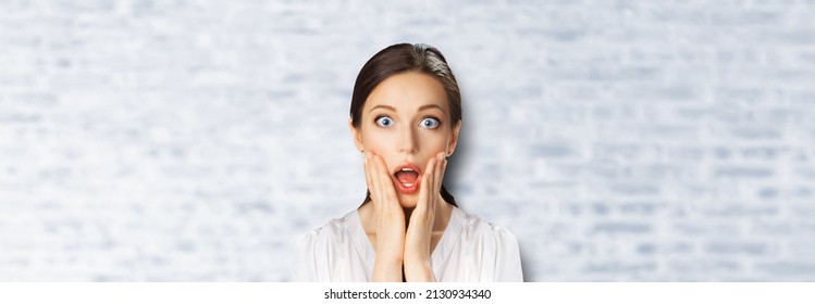 Wow! Excited surprised, astonished very happy woman. Girl with wide opened eyes, open mouth and raise hands. Unbelievable sales, rebates offer, discounts deal studio image. White bricks wall.