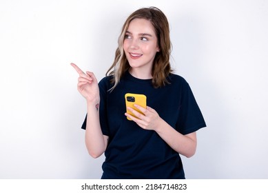 Wow!! excited young caucasian woman wearing black T-shirt over white background showing mobile phone with open hand gesture