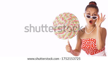 Wow face. Cheerful woman in pin up style with a perfect hair and a make up hold colorful big candy. isolated on white background. Sweets	