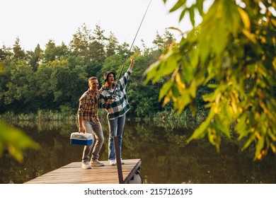 Wow, fish. Unusual romantic date in countryside. Young beautiful couple standing on pier and fishing. Beauty of nature. Summer weekends. Fresh air breathing. Concept of leisure time activity, ad - Powered by Shutterstock