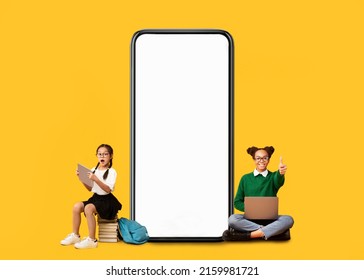 Wow, Great Offer. Excited Multiethnic School Girls Sitting On Floor And Pile Stack Of Books Near Big Giant Cell Screen, Using Pc Laptop And Tablet On Yellow Orange Studio Background, Showing Thumbs Up - Shutterstock ID 2159981721