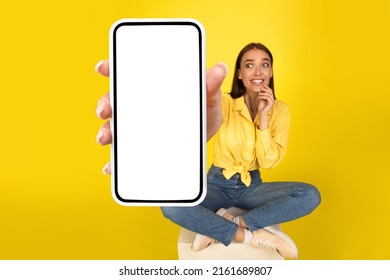 Wow, Great Offer. Excited Surprised Woman Showing Big White Empty Smartphone Screen Close Up To Camera Recommend Cellular App On Orange Yellow Studio Wall, Selective Focus On Hand. Check This Out