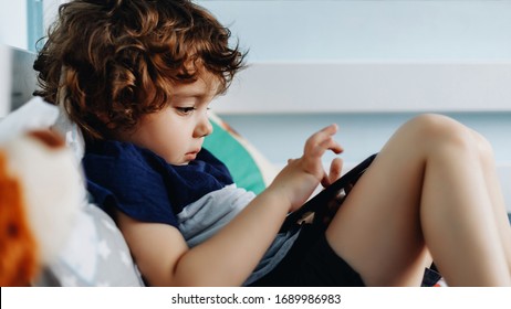 Wow, I Like That Phone. Baby With Smartphone. Boy Sitting In Bed And Playing With Mobile Phone. Calling My Mom. Cute Little Baby Holds Mobile Phone In His Hands And Looking Attentively At Screen.