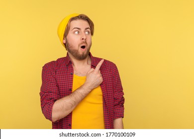 Wow, Look, Advertise Here! Surprised Hipster Guy Pointing Aside And Looking At Copy Space With Shocked Amazed Expression, Showing Blank Yellow Background For Crazy Commercial Idea. Indoor Isolated