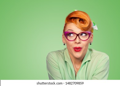 Wow, Look here aside. Closeup red head young woman pretty amazed pinup girl in button shirt excited surprised shocked looking up to side retro vintage 50s hairstyle on green wall. Cute face expression