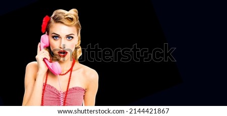 WOW! Portrait studio image - shocked or surprised woman holding phone tube Blonde pinup girl with wide open mouth. Retro vintage concept. Dark black background. Call center. Callcenter. Centre adviser