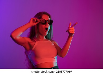 Wow  Portrait young Caucasian beautiful girl in sunglasses isolated over gradient background in neon mixed light  Concept human emotions  facial expression  sales  youth culture  mood  ad  Flyer