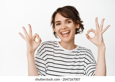 Wow Really Not Bad, Good Choice. Impressed Good-looking Modern 20s Woman In Yellow Sweater, Nod Acceptingly, Squinting Show Okay, Approval Sign, Stand White Background