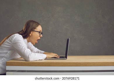 WOW. Side View Of Funny Open Mouthed Woman Looking At Screen Of Laptop Computer With Big Surprise. Shocked Young Girl Wins Amazing Prize, Gets Job Offer Or Receives Email With Good News