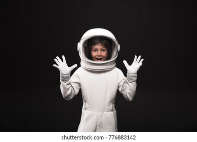 Wow. Waist up portrait of wondered little astronaut in helmet and protective suit is standing while holding something in his hands. He is opening his mouth in wide-eyed surprise. Isolated