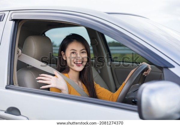 Wow. Young beautiful asian\
women getting new car. she very happy and excited. she sit and\
touching every detail of car. Smiling female driving vehicle on the\
road