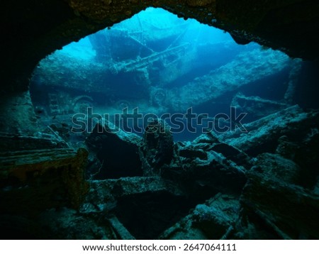 Wrack of the SS Thistlegorm, view from inside a dark cargo bay to the outside, a lonesome wheel standing in the middle