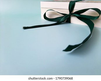 Wrap stack of books with green ribbon bow like a gift on blue background. Copy space.