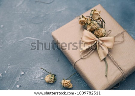 Wrapped brown present box with dry flowers on vintage background