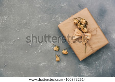 Wrapped brown present box with dry flowers on vintage background