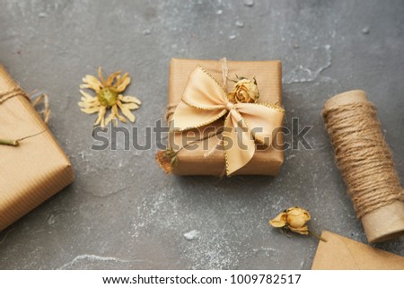 Wrapped brown present box with dry flowers on vintage background