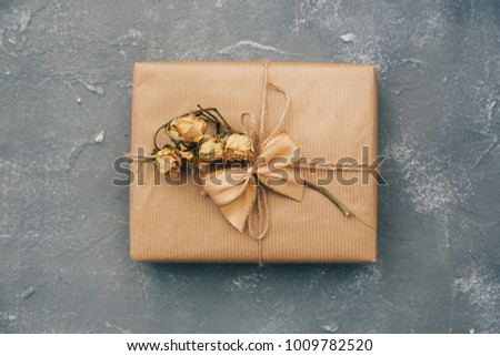 Wrapped brown present box with dry flowers on vintage background