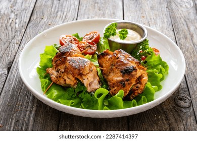 Wrapped chicken breasts filled with mozzarella cheese, spinach and tomato sauce served with green vegetables on wooden table 