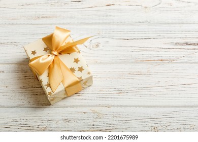 Wrapped Christmas Or Other Holiday Handmade Present In White Paper With Gold Ribbon On Colored Background. Present Box, Decoration Of Gift On Colored Table, Top View With Copy Space.