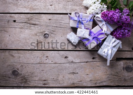 Wrapped  gift boxes with presents  and lilac flowers on aged wooden background. Selective focus. Place for text.