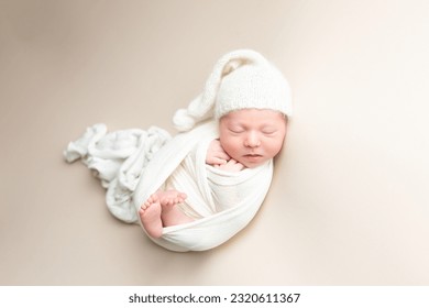 wrapped newborn baby boy on a light background. hat cap on the child. Studio shot of a newborn.