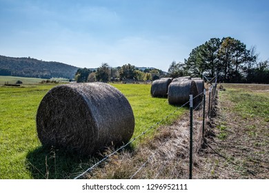 Wrapped Round Hay Bales At The Edge Of A Field Near A Barbed Wire Fence In Rural Appalachia.