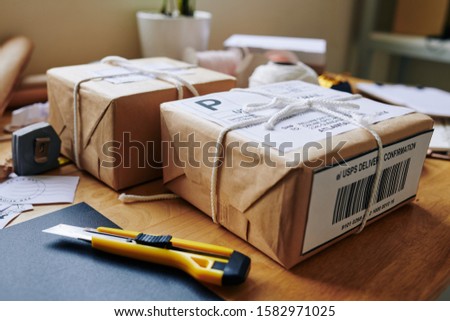 Wrapped and strapped packages ready to be delivered and boxcutter tool on table