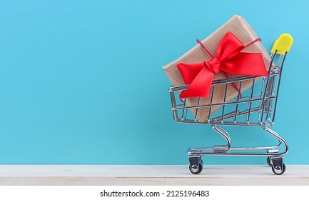 Wrapped vintage gift box in in mini grocery cart on wooden table on blue background with copy space.  - Powered by Shutterstock