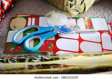 Wrapping Christmas Presents With Paper, Sticky Tape, Scissors And Gift Tags 