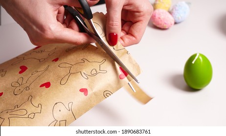 Wrapping Easter gifts on a light background. Wrapping paper with hearts and bunnies. Decorative eggs and red bow - Powered by Shutterstock