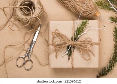 Wrapping Eco Christmas Packages With Brown Paper, String And Natural Fir Branches 