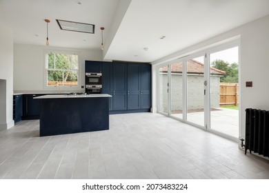 Wratting, England - August 19 2019: Refitted Traditional Looking Kitchen With Built In Appliances, Peninsula Unit With Hob, Ceiling Extractor Hood And Bifold Doors.