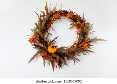 A wreath of branches, decorated with berries, orange leaves, pumpkin and dried flowers. Autumn, harvest or Halloween concept, isolated on white background. - Powered by Shutterstock