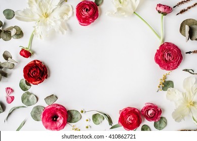 wreath frame with pink and red roses or ranunculus, white tulips and green leaves on white background. Flat lay, top view