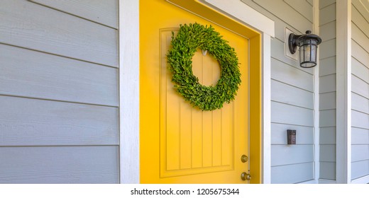 Wreath On Yellow Front Door And A Lamp On A Wall