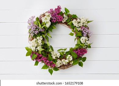 Wreath from purple lilac flowers on white wooden background. Surprise for lovely woman. Natural spring style. Aromatherapy.  Flowers Flat lay, top view. Background with copy space. Spring blossom mood