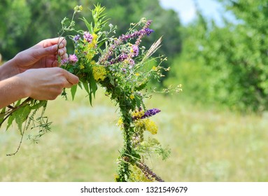 A Wreath Of Spring And Summer Flowers In The Hands Of The Girl. A Woman Creating A Flower Herbs Wreath. Nature. Ivana Kupala Holiday