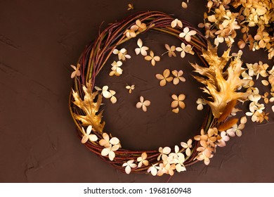 Wreath Of Wicker And Dry Hydrangea Flowers A Lot On Brown Background. Top View. Decor Element With Copy Space For Holiday Card. Grape Vine Wreath.