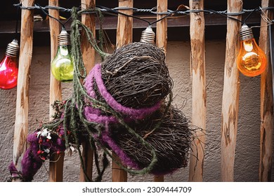 A wreath of wicker in the shape of a heart in front of a wooden fence and a string of brightly colored lightbulbs. - Powered by Shutterstock