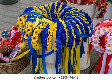 Wreaths of flowers in the colors of the flag of Ukraine and Poland. Blue and yellow (Ukrainian) wreaths and white and red (Polish) wreaths. Colorful head wreaths. Stall with flowers and flower garland