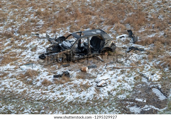 Wreck of a devastated car on a meadow.\
Disassembled car skeleton. Season\
winter.