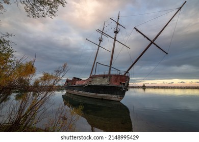The wreckage of La Grande Hermine, a relica carrack, lies abandoned and rotting in the water of Jordan Harbour near St. Catherines, Ontario during sunset.