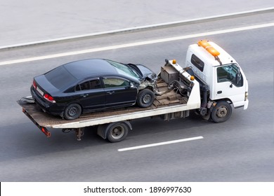 Wrecked car after an accident on a tow truck transported on a highway