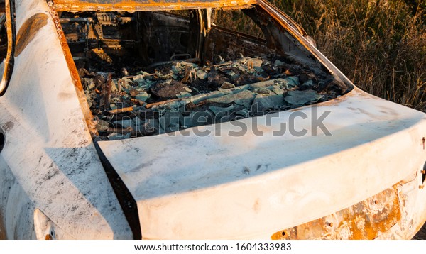 Wrecked car after an explosion or severe fire.\
Melted glass and ash in a burned-out car interior. Abandoned car in\
the forest near the city. The concept of a traffic accident and\
vandalism. Closeup.4k