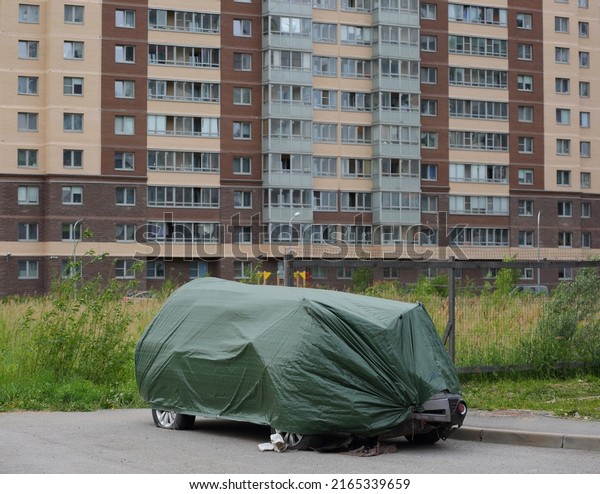 The wrecked car is covered\
with a green cover, Soyuzny Prospekt, Saint Petersburg, Russia,\
June 2022