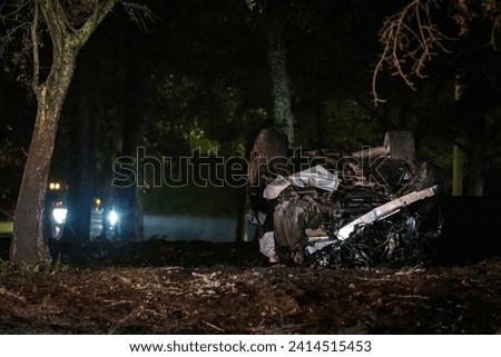 Wrecked car upside down after accident at night in the trees