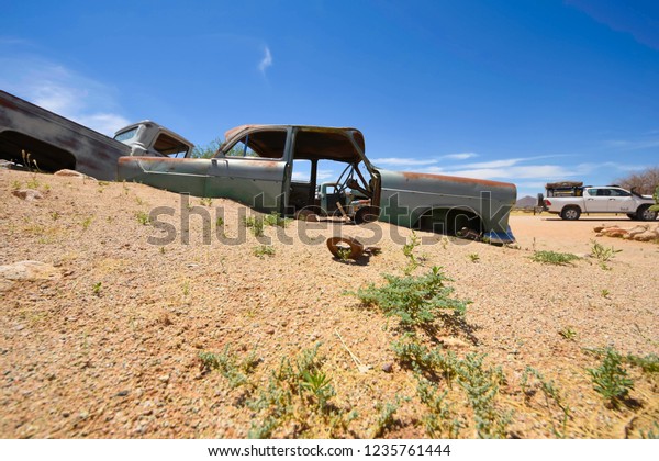 Wrecked cars lie abandoned in the desert\
surrounding Solitaire in\
Namibia.