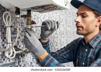 Wrench always with you. Worker set up electric heating boiler at home. Close-up of young handyman - Shutterstock ID 1310136589