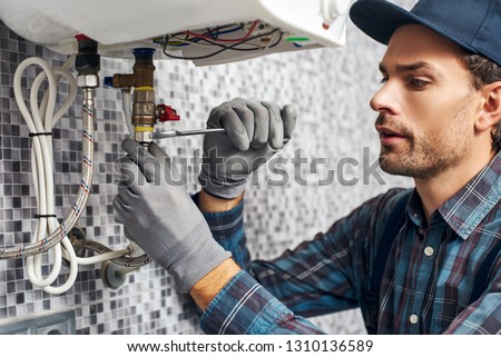 Wrench always with you. Worker set up electric heating boiler at home. Close-up of young handyman