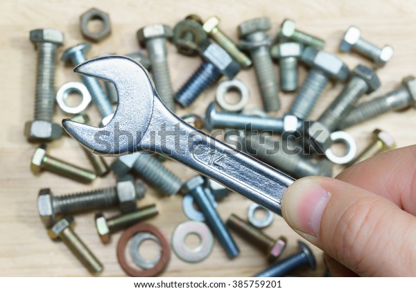 Wrench\
in hand with blur of nuts and bolts in\
background.